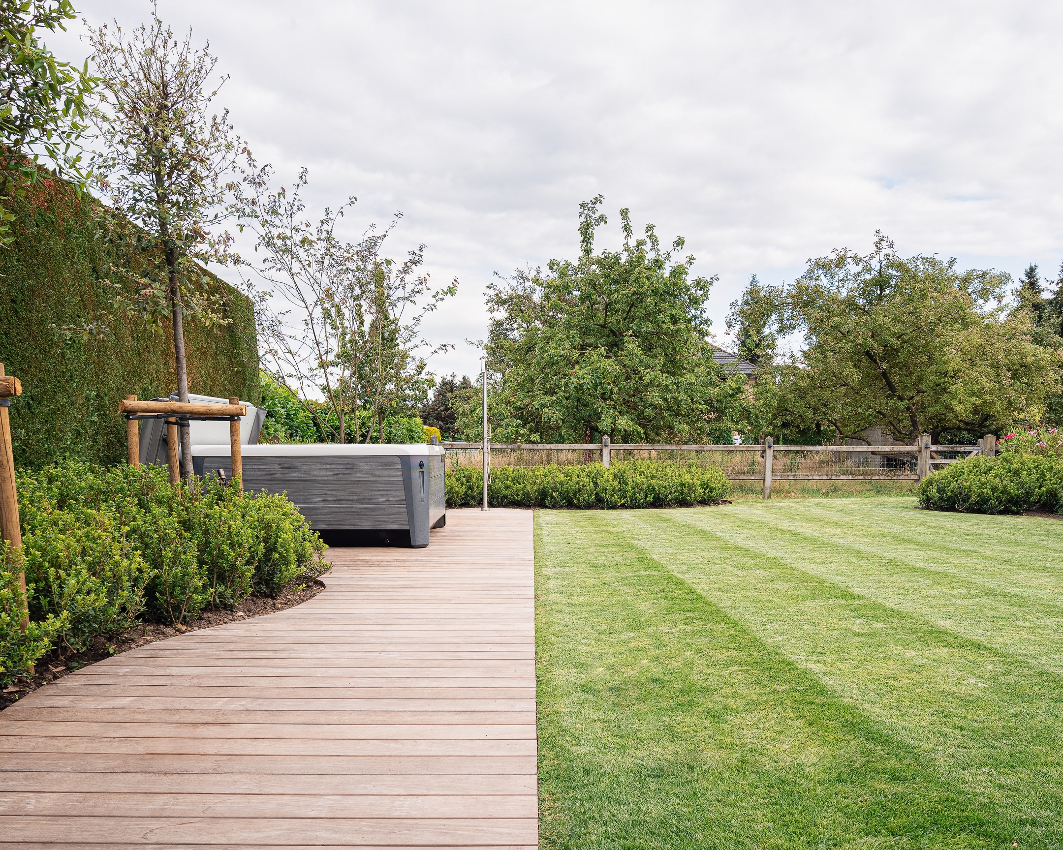 Een tuin met gazon en een pad naar een jacuzzi.