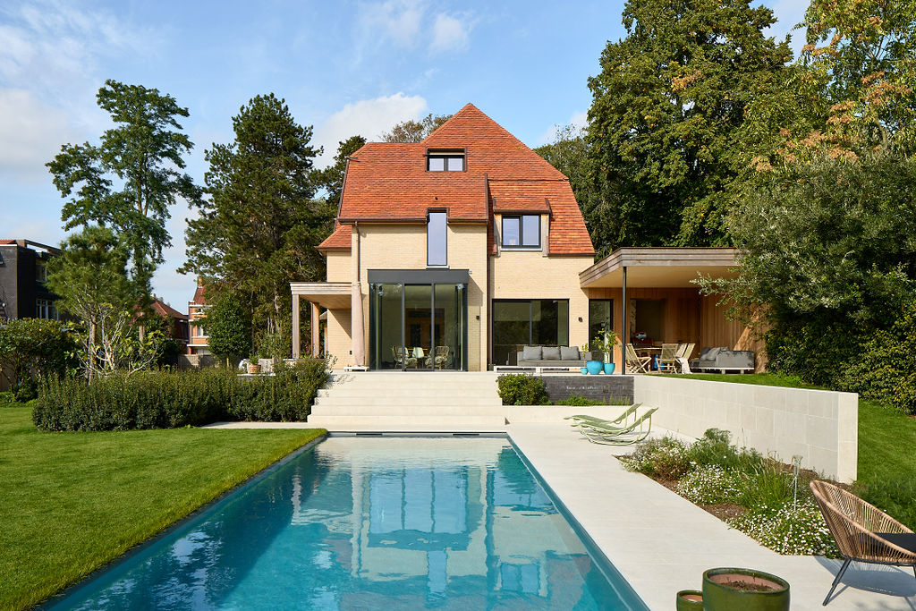 Een huis met een tuin, zwembad en een verhoogd terras.