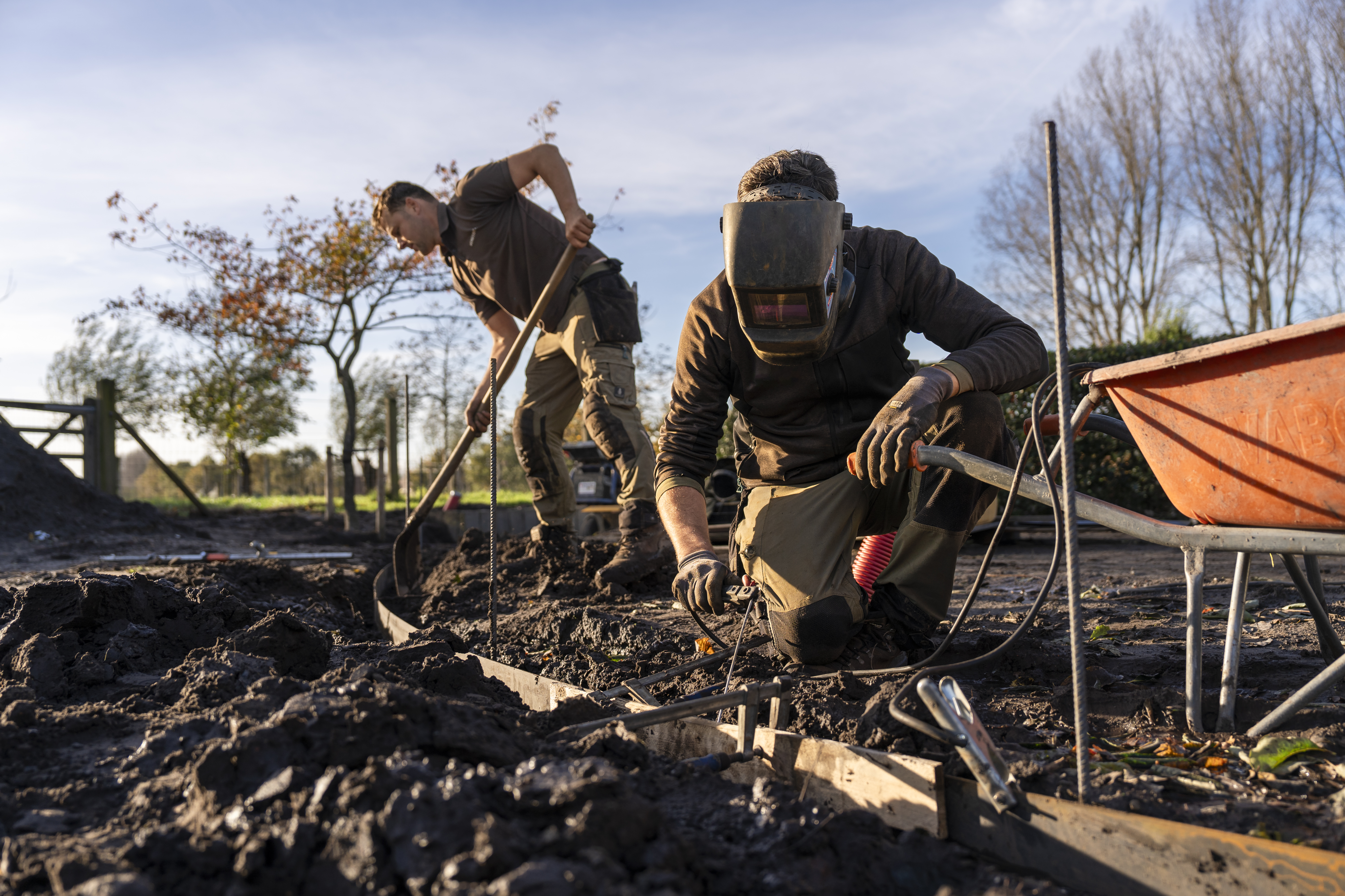 Twee werkmannen die een tuin aan het aanleggen zijn.