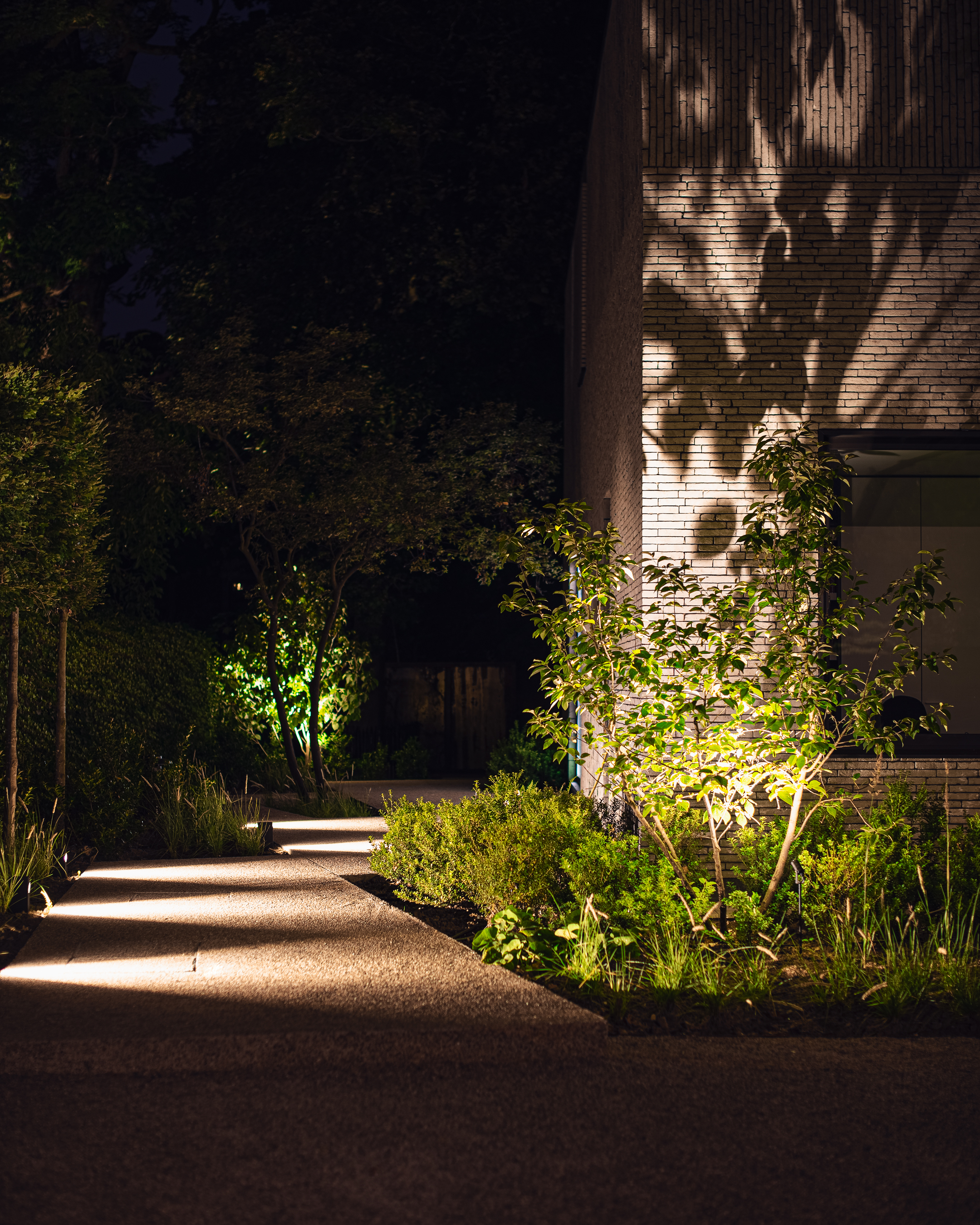 Een verlicht pad naar de achterkant van een woning.
